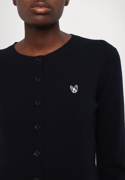 Mørkeblå ullcardigan med rund hals, frontknapper og et brodert dyremotiv på brystet. Glatt tekstur.
