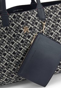 Torebka typu tote w granatowo-beżowym wzorze od Tommy Hilfigera z złotym logo i dołączoną granatową skórzaną saszetką na zamek.