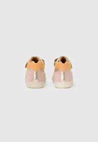 Sneaker aus einer Materialmischung: rosa Wildleder, metallische goldene Akzente und hellorangefarbene Fersenschlaufen. Verfügt über einen Klettverschluss und eine abgerundete Form.