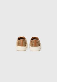 Sneakers retrò con un esterno marrone chiaro testurizzato, accenti beige e una suola in gomma crema. Presenta un sottile motivo di design sul materiale.