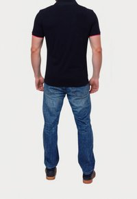 Námořnické polo triko s krátkými rukávy a červenými detaily, spárované s modrými džíny. Oblečení má uvolněný střih a jednoduchý design.