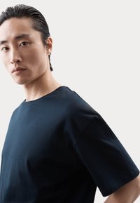 T-shirt corto a maniche corte blu scuro con scollatura rotonda, realizzato in tessuto morbido, caratterizzato da una vestibilità rilassata e delicati dettagli di cucitura.