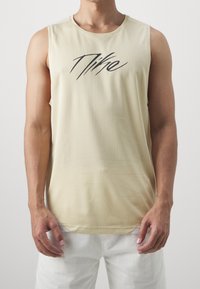 Mouwloze beige mesh sporttanktop met zwart merklogo aan de voorkant in het midden. Beschikt over een ronde hals en een ontspannen pasvorm.
