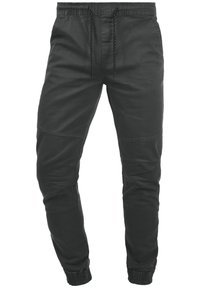 Mustat kapeat juoksuhousut, jotka on valmistettu puuvillasta. Niissä on joustava vyötärönauha, säädettävä kiristysnauha ja resorit lahkeensuissa; niissä on myös saumalistaus.