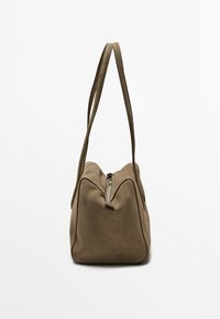 Borsa in suede verde oliva con due manici lunghi, forma triangolare e chiusura con zip superiore. Texture liscia e design minimalista.