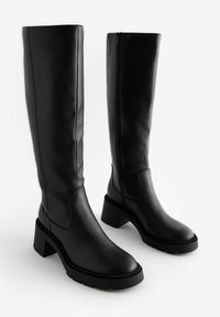 Knee-high mustad nahkkingad, millel on plokkkonts, sile tekstuur, külgzipper ja vastupidav, mustriline tall, et tagada haarduvus.