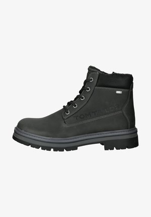 Schwarze Lederstiefel für den Knöchel mit texturiertem Finish, ausgestattet mit sechs Metallösen, einem gepolsterten Kragen und einer robusten Gummisohle. "TOM TAILOR" ist seitlich eingestanzt.
