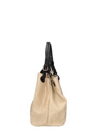 Beige geweven totebag met een gestructureerde afwerking, voorzien van zwarte leren handvatten en metalen accenten, ontworpen met een ruime, slungelige vorm.