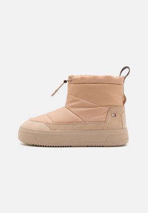 Beżowe ocieplane buty śniegowe z miękką tkaniną w górnej części, gumową podeszwą i elastycznym sznurkiem dla pewnego dopasowania, z małym akcentem logo.