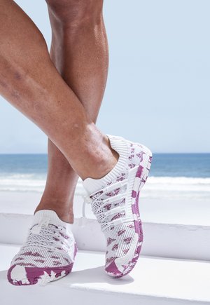 White and purple athletic shoes with a textured knit upper, elastic laces, and a patterned sole, designed for comfort and flexibility.