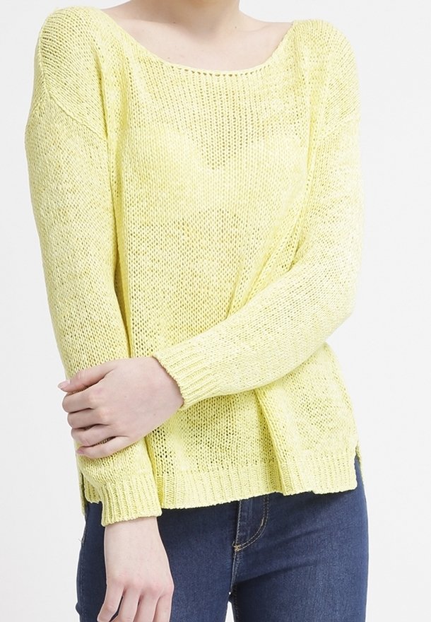 Pull en maille jaune avec un décolleté large et des manches longues, offrant une coupe ample et un ourlet côtelé, associé à un jean foncé.