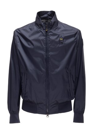 Giacca leggera blu navy con zip frontale, colletto alto, polsini elastici, due tasche frontali con zip e un piccolo logo rettangolare sul petto.