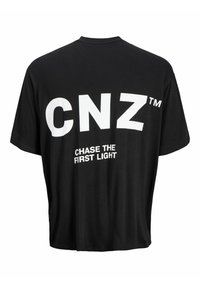 Camiseta de algodón negra con gran texto blanco "CNZ™" y "PERSEGUIMOS LA PRIMERA LUZ" en la parte posterior. Corte holgado, cuello redondo, mangas cortas.