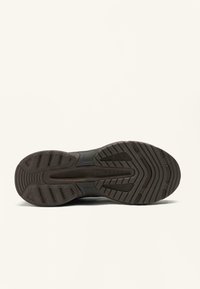 Black athletic shoe sole with textured rubber for grip, featuring a wavy pattern and raised sections for traction and stability.