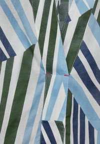 Patterned fabric with blue, green, and white diagonal stripes. Features visible stitching with a pink accent. Soft, lightweight texture.