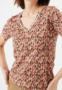 Tričko s krátkým rukávem ve tvaru V v mnohobarevném abstraktním vzoru v odstínech hnědé, růžové a bílé; jemná tkanina s hladkým povrchem.