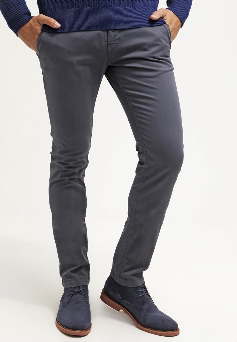 Grijze slim-fit broek van gladde stof, met een strak ontwerp en zijzakken, gecombineerd met marineblauwe suède schoenen en een blauwe trui.