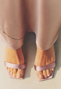 Sandali ciabatta rosa in satin con punta aperta, cinturini larghi, tacco basso e design con punta quadrata, abbinati a unghie dei piedi in tonalità chiare.