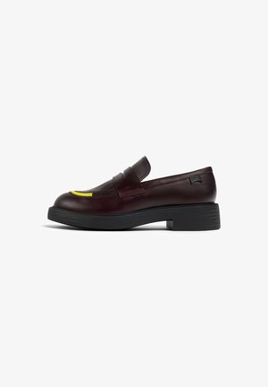 Mocassino in pelle bordeaux con punta arrotondata, suola piatta nera e un accento giallo sul gambale. Design minimalista con dettagli di cucitura.
