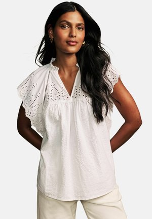 Weiße Baumwollbluse mit gerüschten Ärmeln, versehen mit Lochstickerei und einem V-Ausschnitt. Leichter Stoff mit strukturierter Oberfläche.
