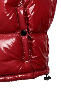 Rote Pufferweste mit glänzender Oberfläche, featuring horizontal gesteppte Abschnitte, einem schwarzen Druckknopf und einem Kordelzug am Saum.