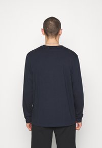Marineblaue Langarmshirt aus glattem Stoff. Mit Rundhalsausschnitt, lockerer Passform und minimalen Nahtdetails auf der Rückseite.