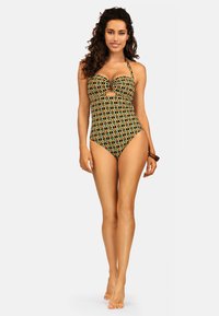 Jednoczęściowy strój kąpielowy z żywym geometrycznym wzorem w kolorze żółtym, zielonym i czarnym, z dekoltem w kształcie serca i wycięciem.
