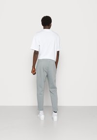 Grå joggers med en avsmalnande passform och elastisk midja, kombinerat med en vit T-shirt med kort ärm. Bärs med vita sneakers.