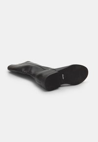 Black knee-high boots made of smooth leather with a block heel. Features a rounded toe and a textured rubber sole. Brand name on the insole.