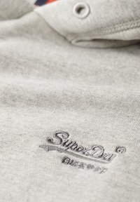Polo shirt de algodón gris con una superficie texturizada y un logo oscuro bordado de "Superdry" en el pecho, con un diseño de collar abotonado.