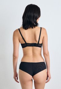 Zwart lingerieset met een sheer beha en bijpassende hooggewaistieve slips. De beha heeft verstelbare bandjes en een sluiting aan de achterkant met een strikdetail.