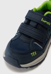 Granatowe buty sportowe z zielonymi akcentami, wykonane z teksturowanej tkaniny i materiałów syntetycznych, z rzepami oraz wzmocnionym noskiem.