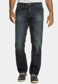 Jeans de mezclilla de color azul oscuro con un corte de pierna recta, costuras en contraste, cierre de botón, diseño de cinco bolsillos y un ligero desgastado en los muslos.