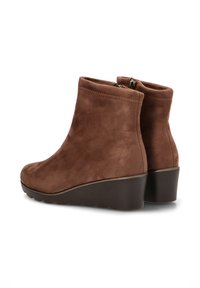 Botas de tobillo de ante marrón con tacón en cuña, cierre de cremallera en la parte posterior y textura suave. Punta redondeada y detalles de costura simples.