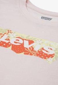 Ροζ βαμβακερό T-shirt με έντονο γραφικό από φράουλες, λουλούδια και το λογότυπο «Levi's» σε λευκό στο μπροστινό μέρος.