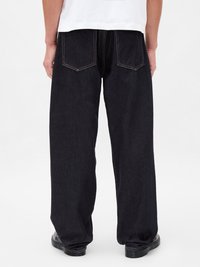 Voľné tmavé džínsy so strihom rovn�ého nohavice, s zadnými vreckami a viditeľným žltým stehom. Materiál sa zdá byť odolný denim.