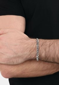 Bracciale in catena d'argento con anelli ovali e rotondi alternati, indossato su un polso. Il design presenta una finitura lucida e un aspetto leggero.