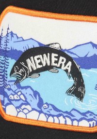 Black cap featuring a colorful embroidered patch of a fish, blue water, and mountains, framed by an orange border, with "NEW ERA" text.