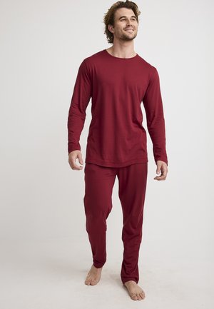 Rotes Oberteil mit langen Ärmeln und passende Hose aus weichem, atmungsaktivem Stoff. Das Shirt hat einen runden Ausschnitt; die Hose hat eine lockere Passform.