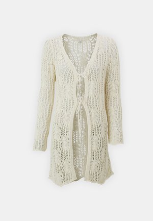 Cardigan lavorato a maglia in bianco sporco, con apertura frontale e chiusura a legaccio. Presenta un design in pizzo e maniche lunghe. Leggero con una finitura testurizzata.