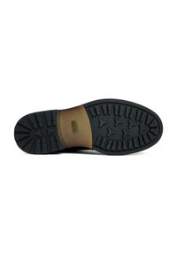 Black rubber outsole with deep treads for grip, featuring a tan midsole labeled "VEGAN." Smooth texture on the midsole with structured detailing.