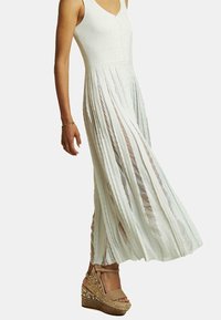Abito maxi bianco a coste con corpetto con bottoni e gonna plissée, indossato con zeppe espadrillas beige con una piattaforma intrecciata e cinturino alla caviglia.