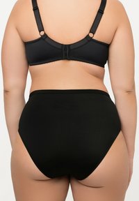 Soutien-gorge noir avec une finition lisse, des bretelles réglables et une fermeture à crochets. Sous-vêtements noirs taille haute avec une texture douce et des détails de couture minimaux.