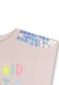 Pale pink T-shirt with a rounded neckline, featuring blue and iridescent heart-shaped sequins along the shoulder and colorful text.