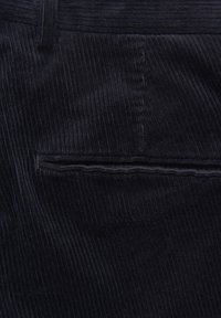 Musta veltin kangas, jossa pystysuorat uritukset, suora vyötärönauha ja pieni, ommeltu takatasku.