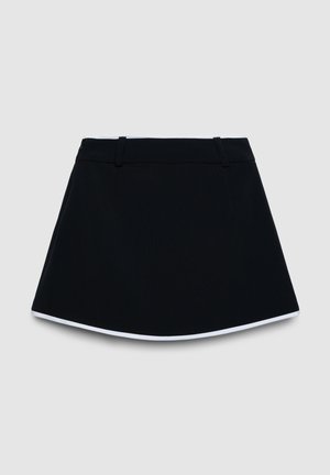 Jupe noire trapèze avec bordure blanche le long de l'ourlet et passants de ceinture sur la taille, présentée sur un fond gris clair.