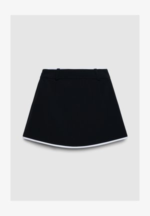 Jupe noire trapèze avec bordure blanche le long de l'ourlet et passants de ceinture sur la taille, présentée sur un fond gris clair.