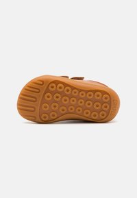 Braune Gummisohle mit strukturiertem Oberflächenmuster aus kreisförmigen Mustern und Rillen für besseren Grip. "Camper"-Logo auf der Seite geprägt.