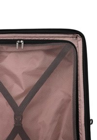 Comparto della valigia aperto con rivestimento in tessuto rosa, cinturini elastici neri e un divisorio in rete con zip e due tiratori argentati.