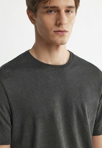 Mørkegrå t-shirt med korte ærmer, fremstillet af et blødt stof. Har en rund hals og en let struktureret overflade med en afslappet pasform.